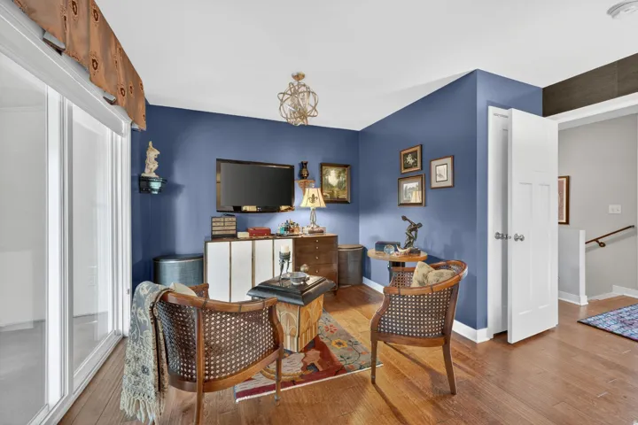 Primary bedroom seating area featuring engineered hardwood flooring, a contemporary chandelier