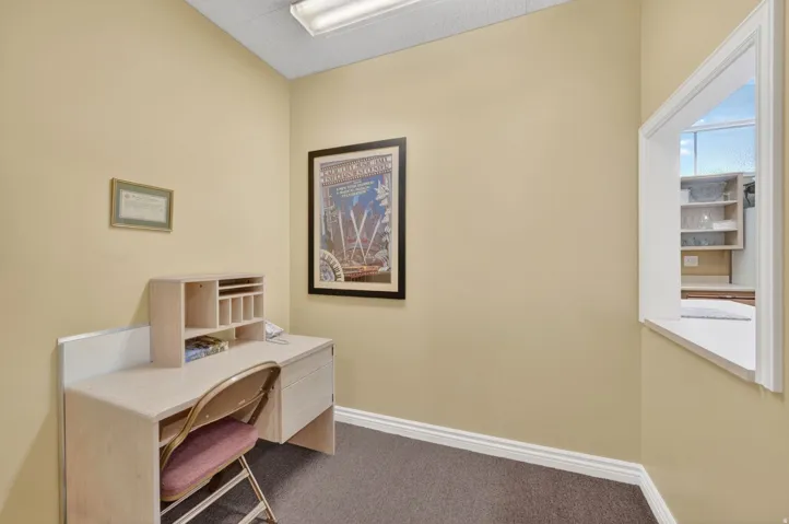 Club house office area featuring a service window, drop ceiling with fluorescent lighting, and neutral-toned walls
