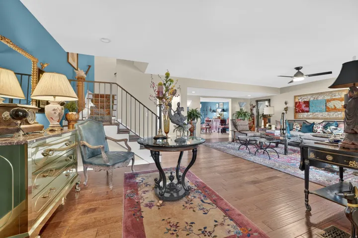 Open-concept living space featuring engineered hardwood flooring, a contemporary ceiling fan, and a staircase with custom railing