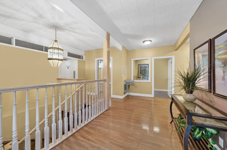 Club House interior hallway featuring hardwood-finish flooring extending throughout the upper landing with white baluster railing