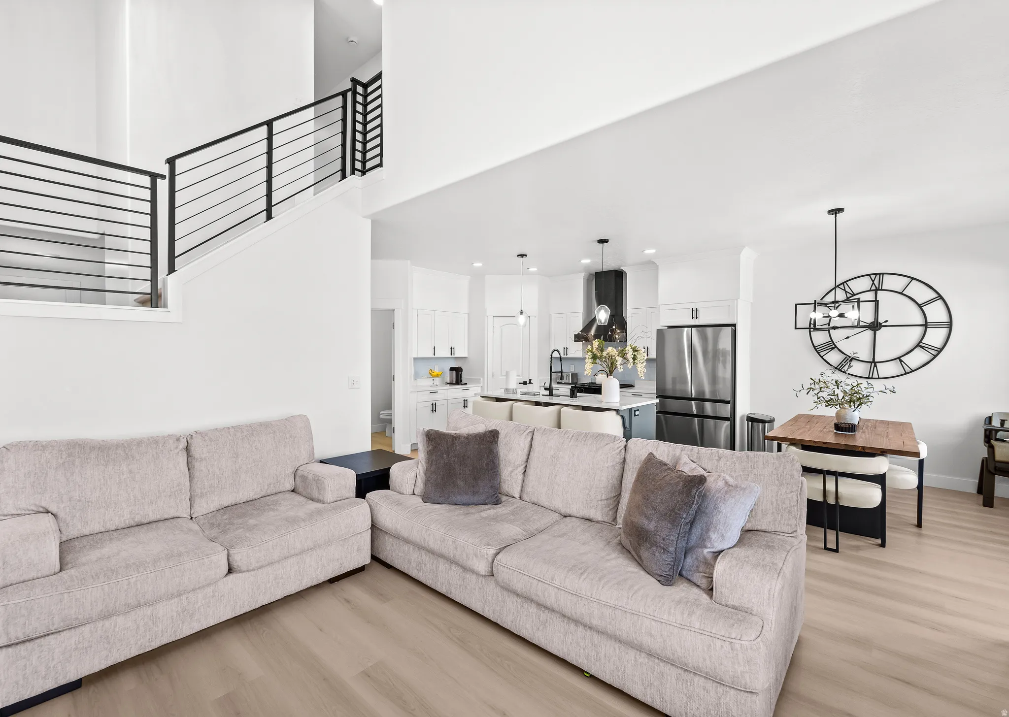 Open-concept living space featuring high ceilings, wood-finish flooring, and a modern staircase with black metal railings