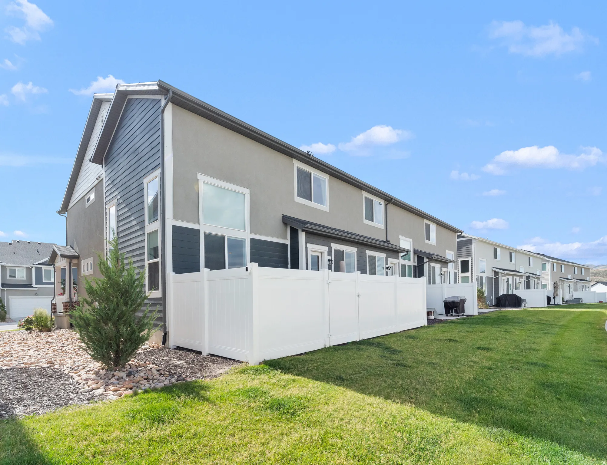 End-unit townhome with multi-textured exterior, privacy fencing, and an expansive grassy area
