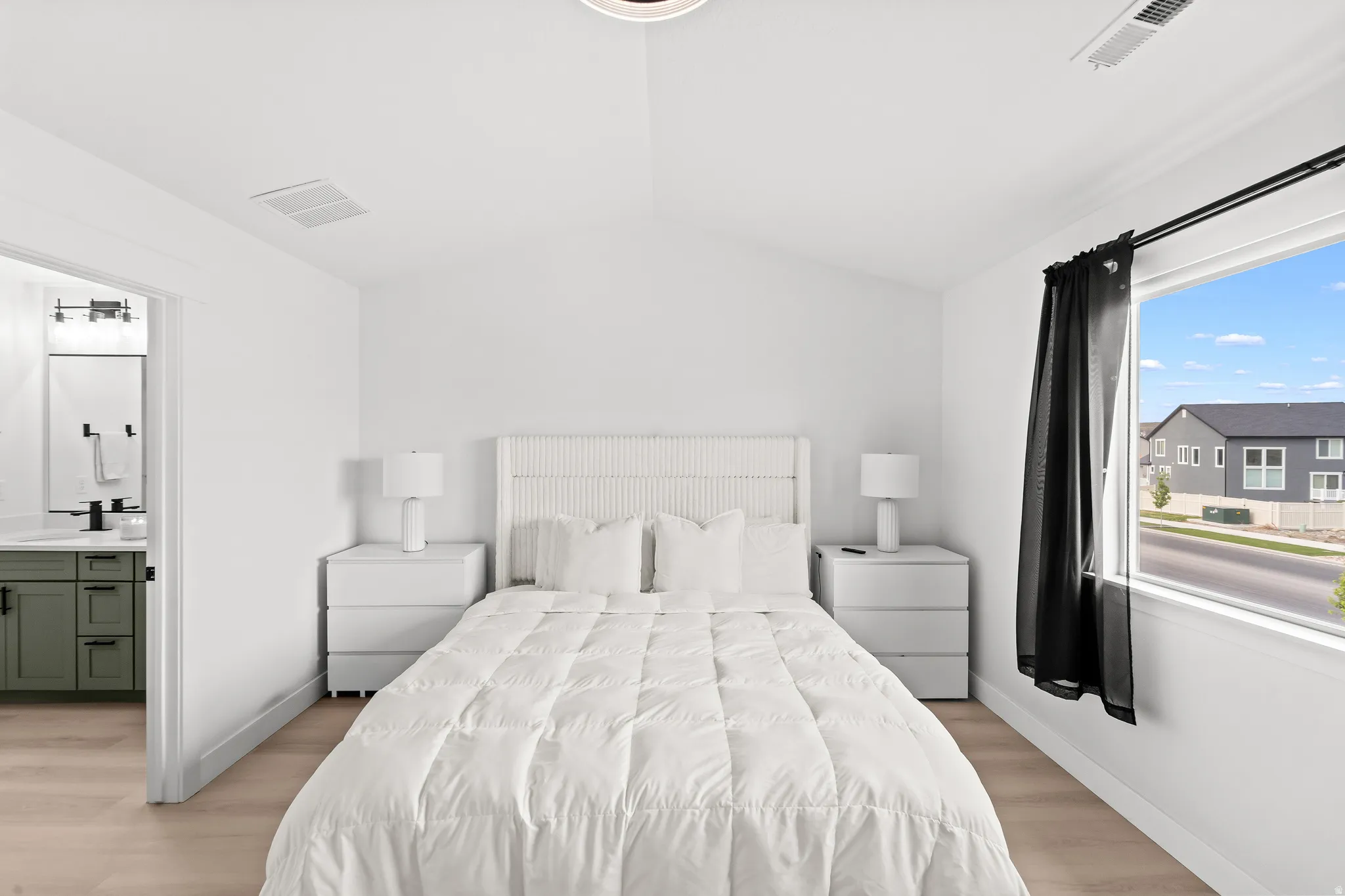 Bright room featuring light wood-finish flooring, a vaulted ceiling, and a large window