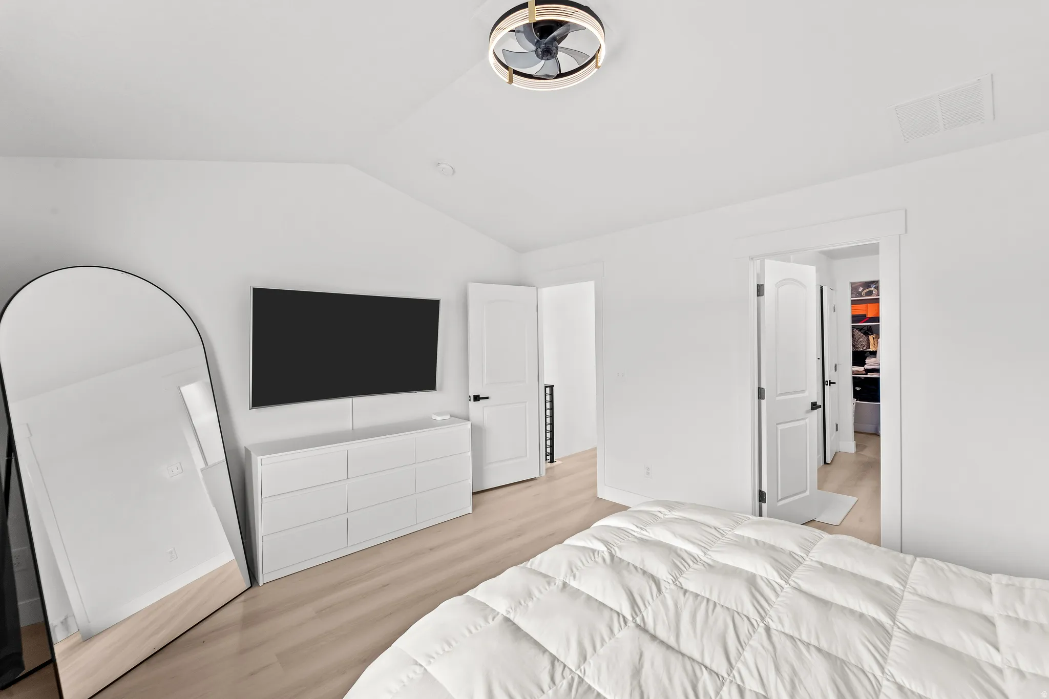 Vaulted ceiling room with light wood-finish flooring