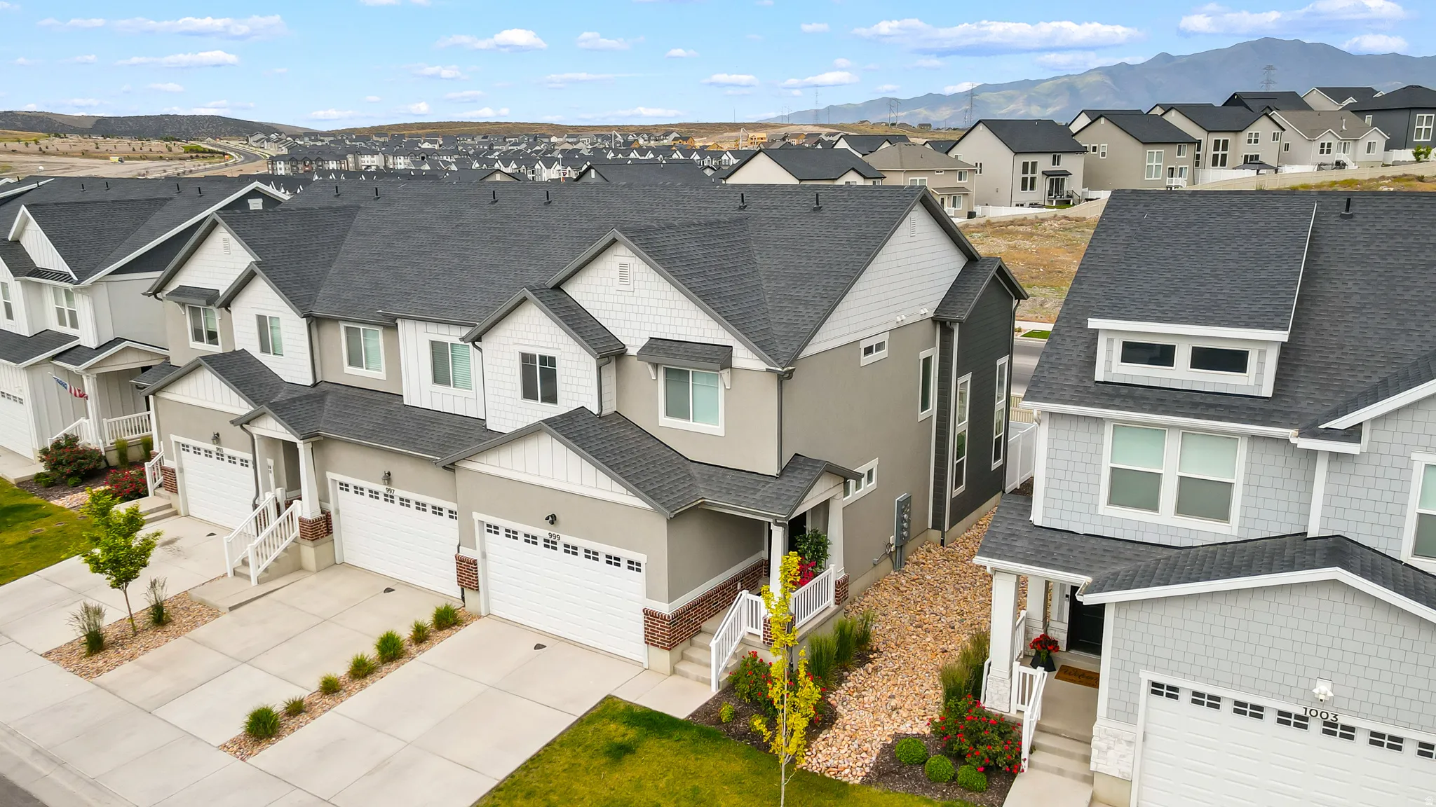 Contemporary townhome featuring a two-car garage, white railing entry, and dark grey roofing