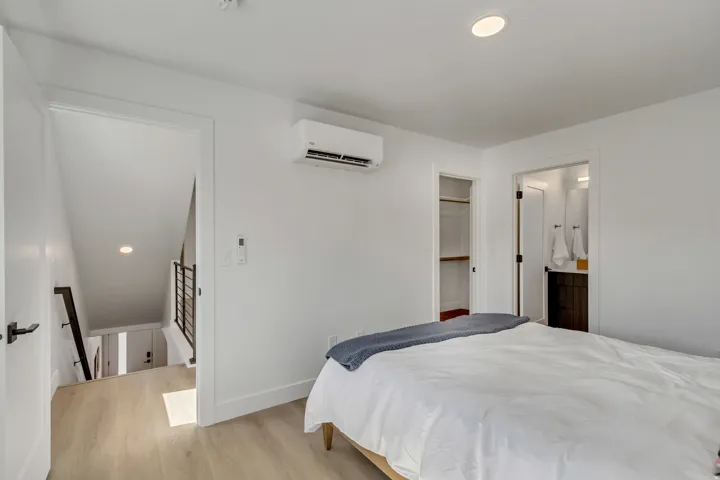 Bedroom with light wood-finish flooring, recessed lighting, and a wall-mounted mini-split HVAC unit