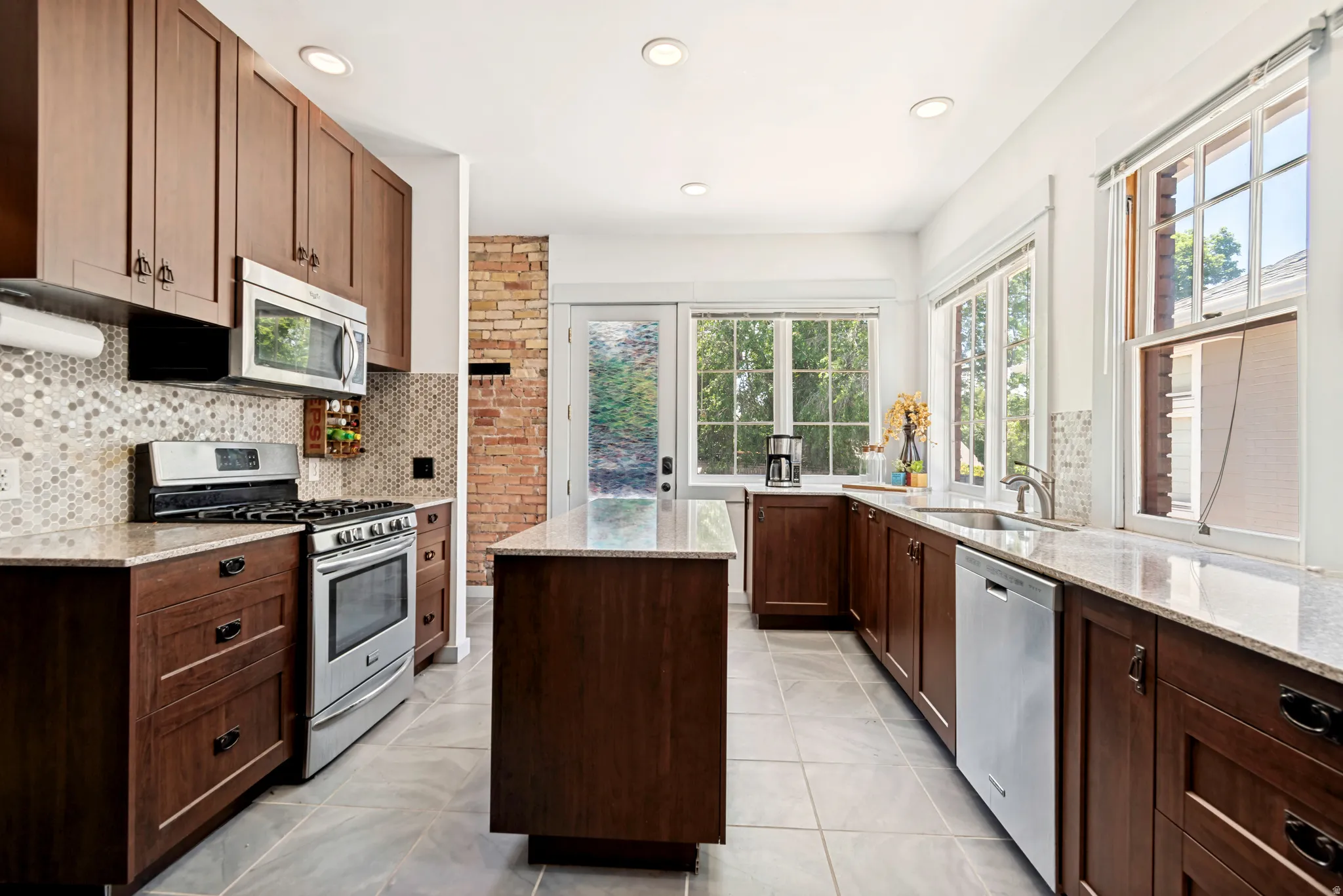 Kitchen featuring dark wood cabinetry, light-colored granite countertops, and stainless steel appliances