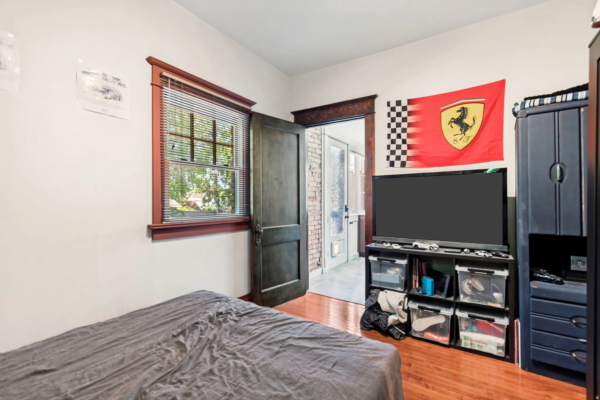 Interior space featuring wood-finish flooring, white painted walls, and a window with blinds