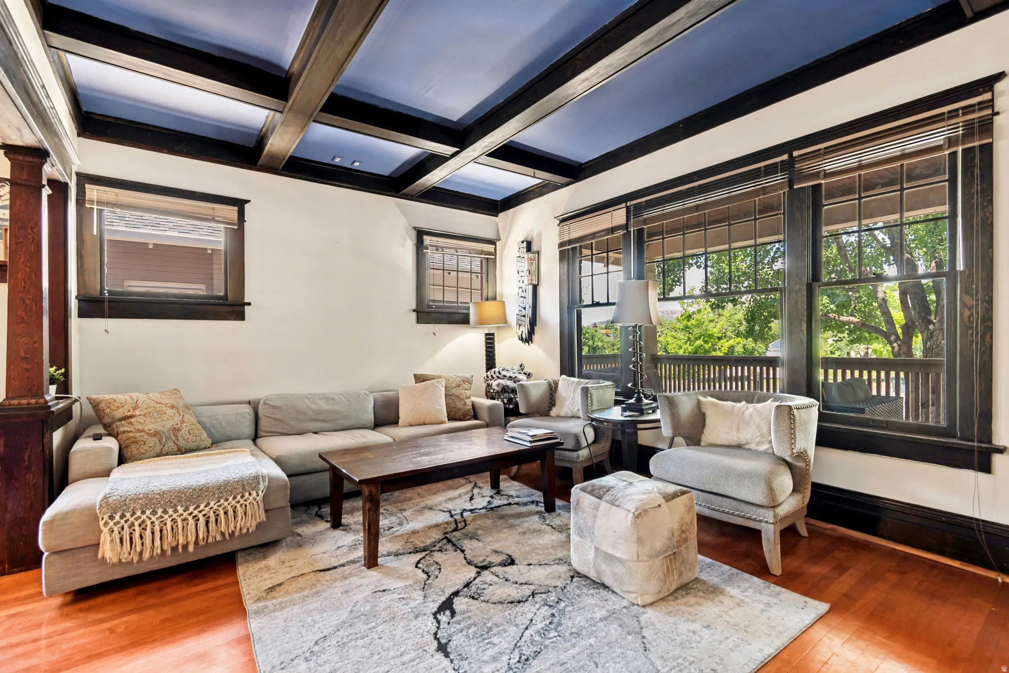 Living area featuring a coffered ceiling with a blue inset, wood-finish flooring, and expansive windows