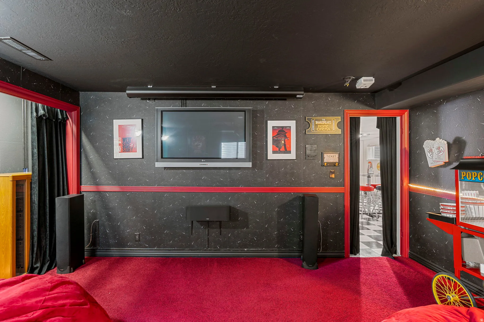 Dedicated entertainment space featuring dark textured wall coverings with a red accent stripe and coordinating red carpeting