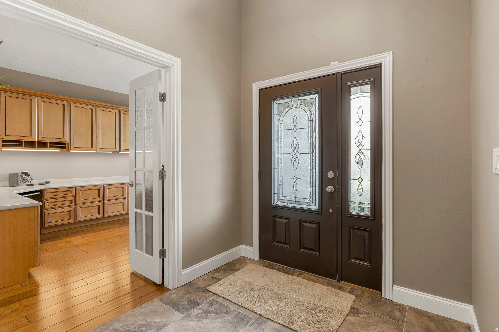 Entryway featuring a dark wood-finish door with decorative leaded glass, an accompanying sidelight with leaded glass, and stone-look tile flooring