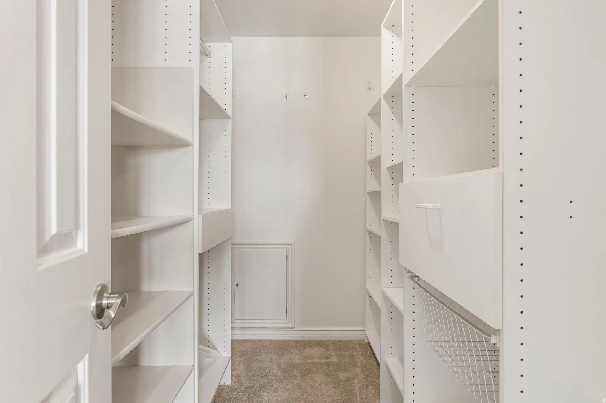 Walk-in closet featuring built-in white shelving, integrated drawers, and a wire pull-out basket