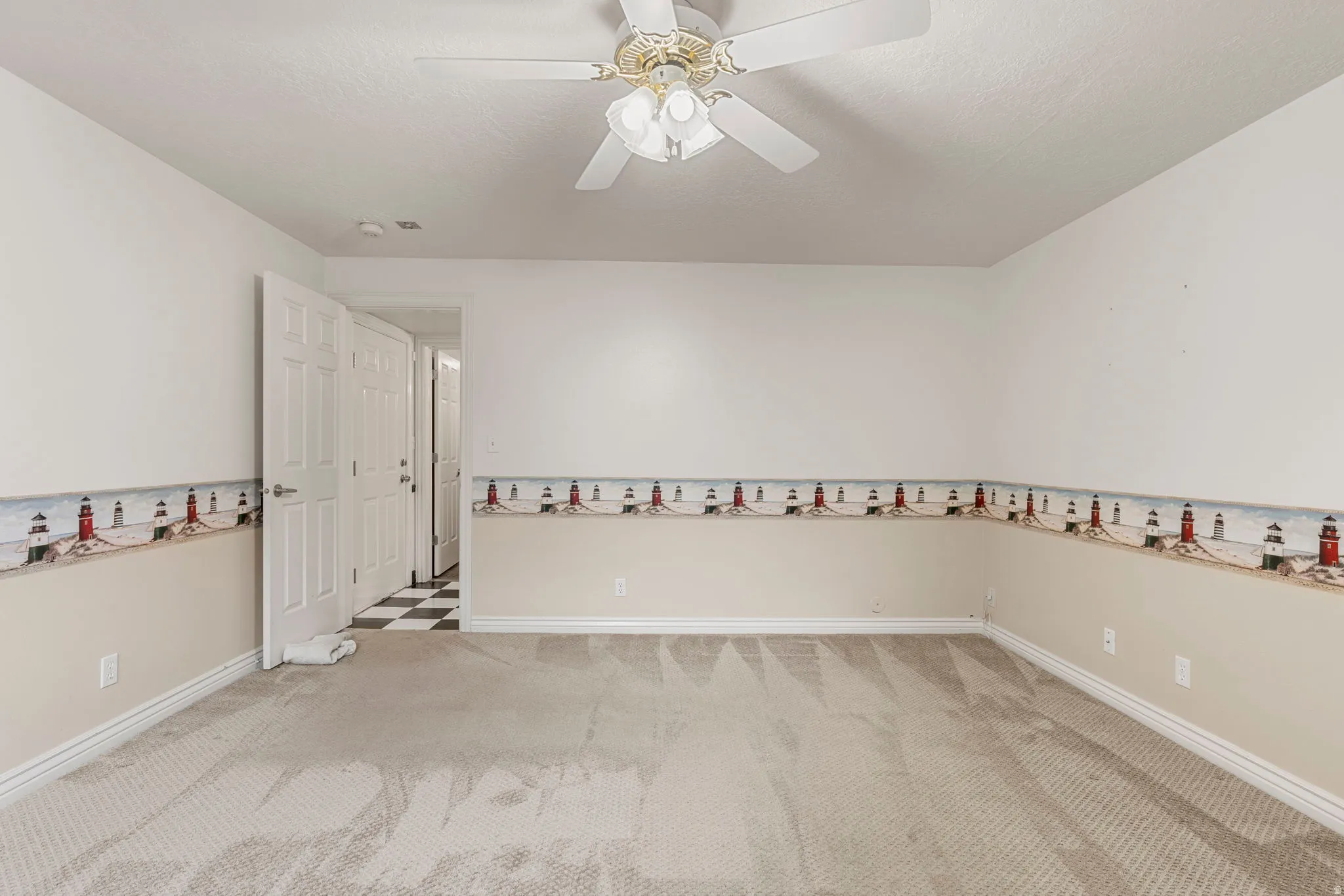 Carpeted interior room with a white ceiling and a ceiling fan