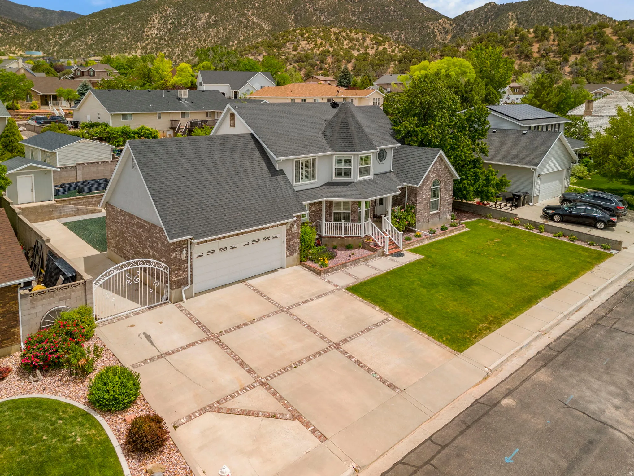 Two-story residence featuring a gray exterior with stone accents, a covered front porch, and a two-car garage