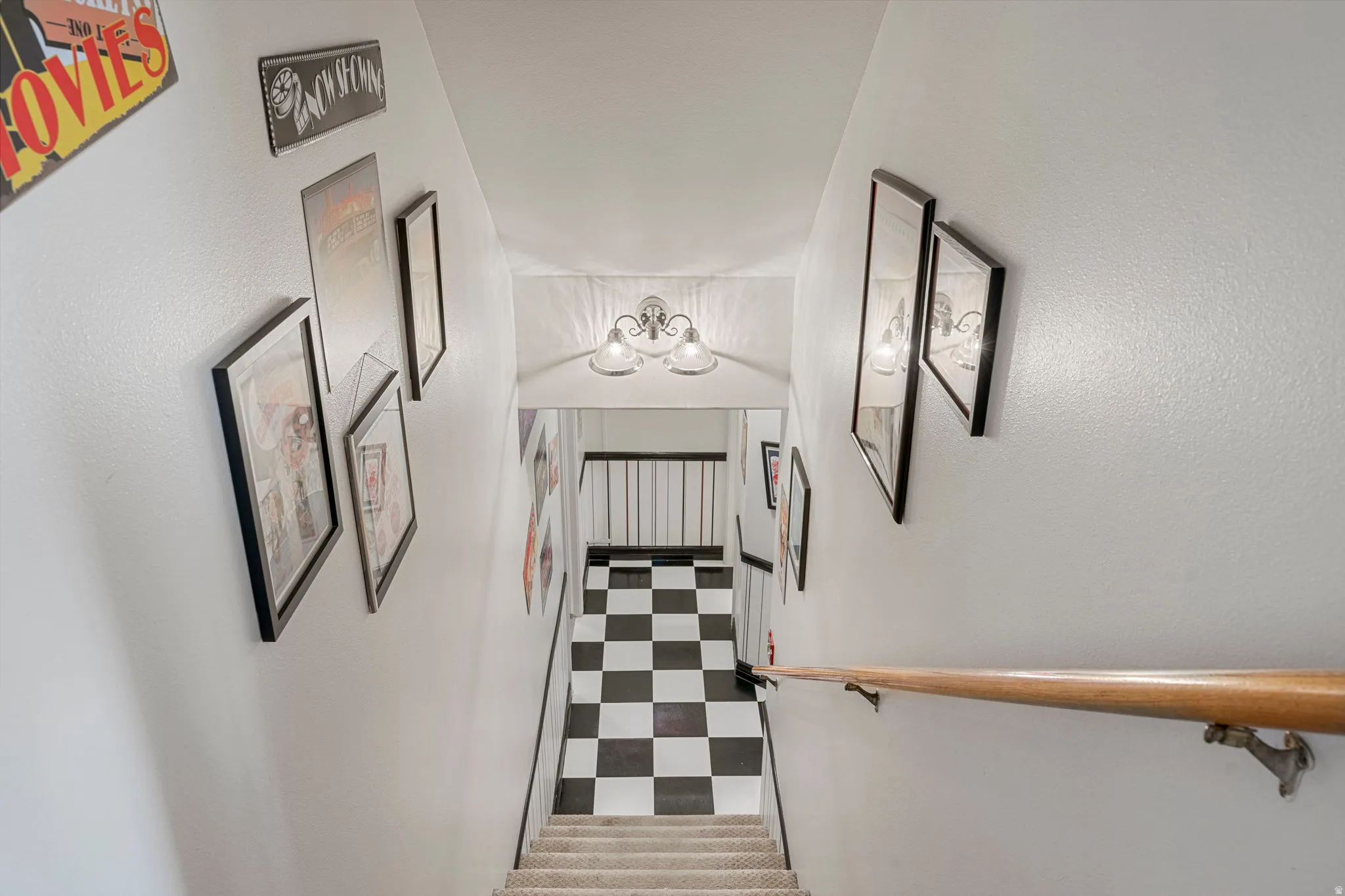 Stairwell with checkered flooring and a light-toned handrail