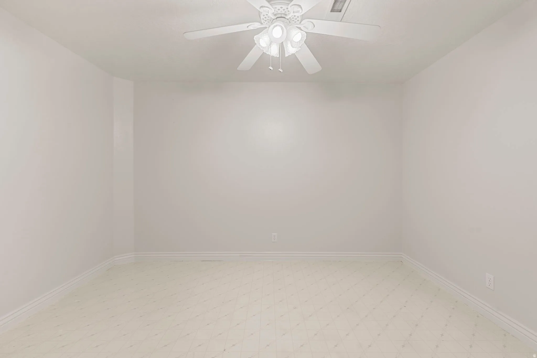 Bright room featuring light-toned walls, ceiling fan with integrated lighting, and patterned flooring