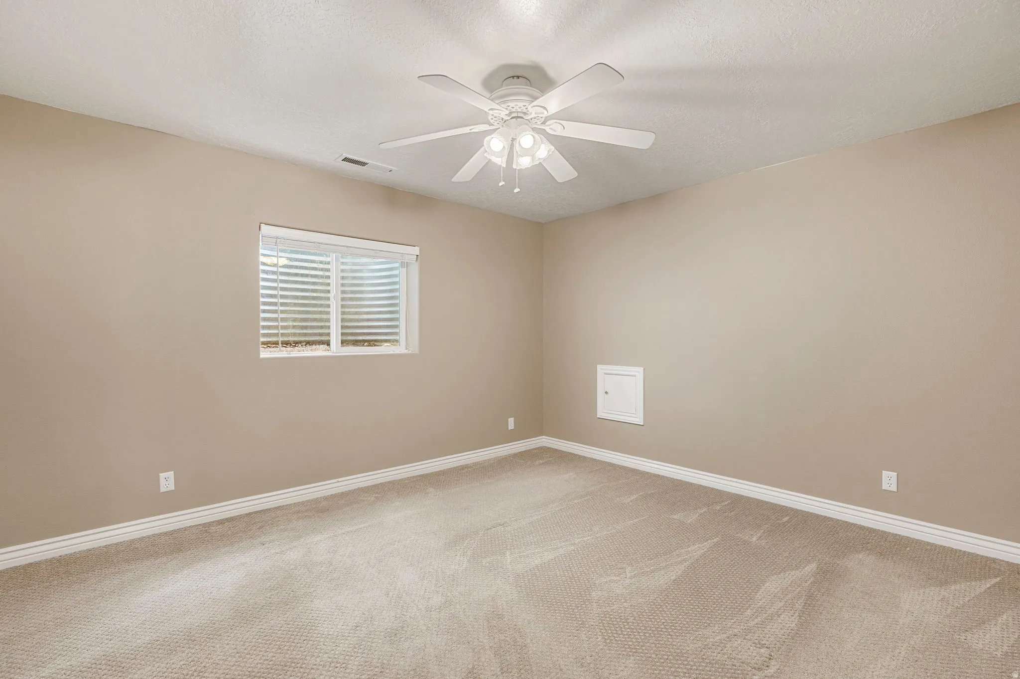 Carpeted room featuring a ceiling fan with integrated lighting, a window with horizontal blinds, and neutral-toned wall paint