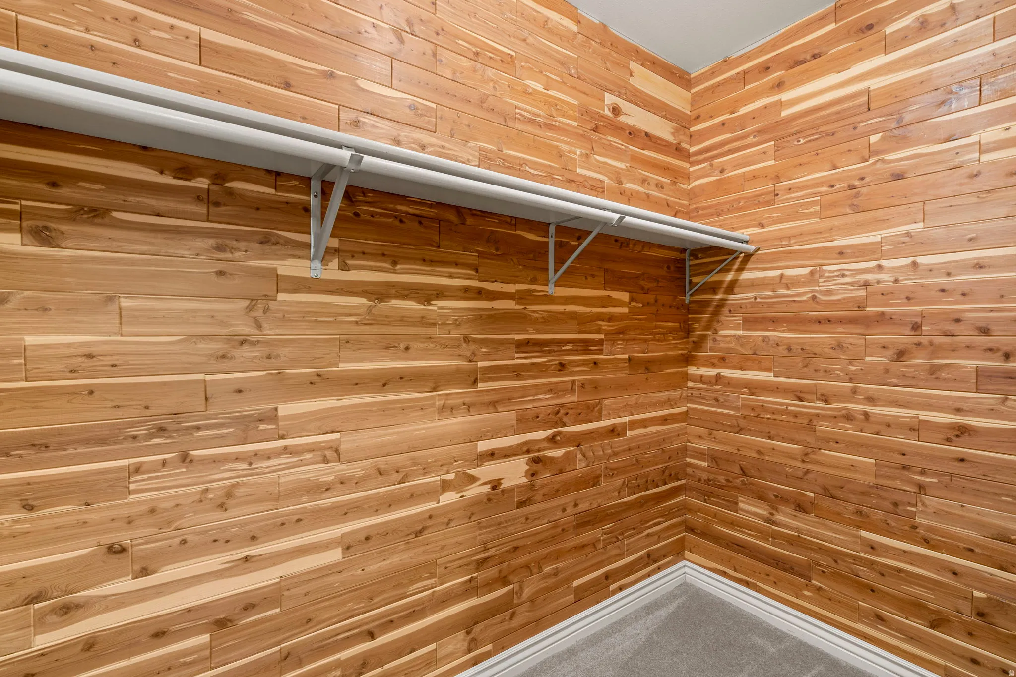 Cedar-paneled walls in a dedicated closet space, featuring built-in shelving and a clothing rod
