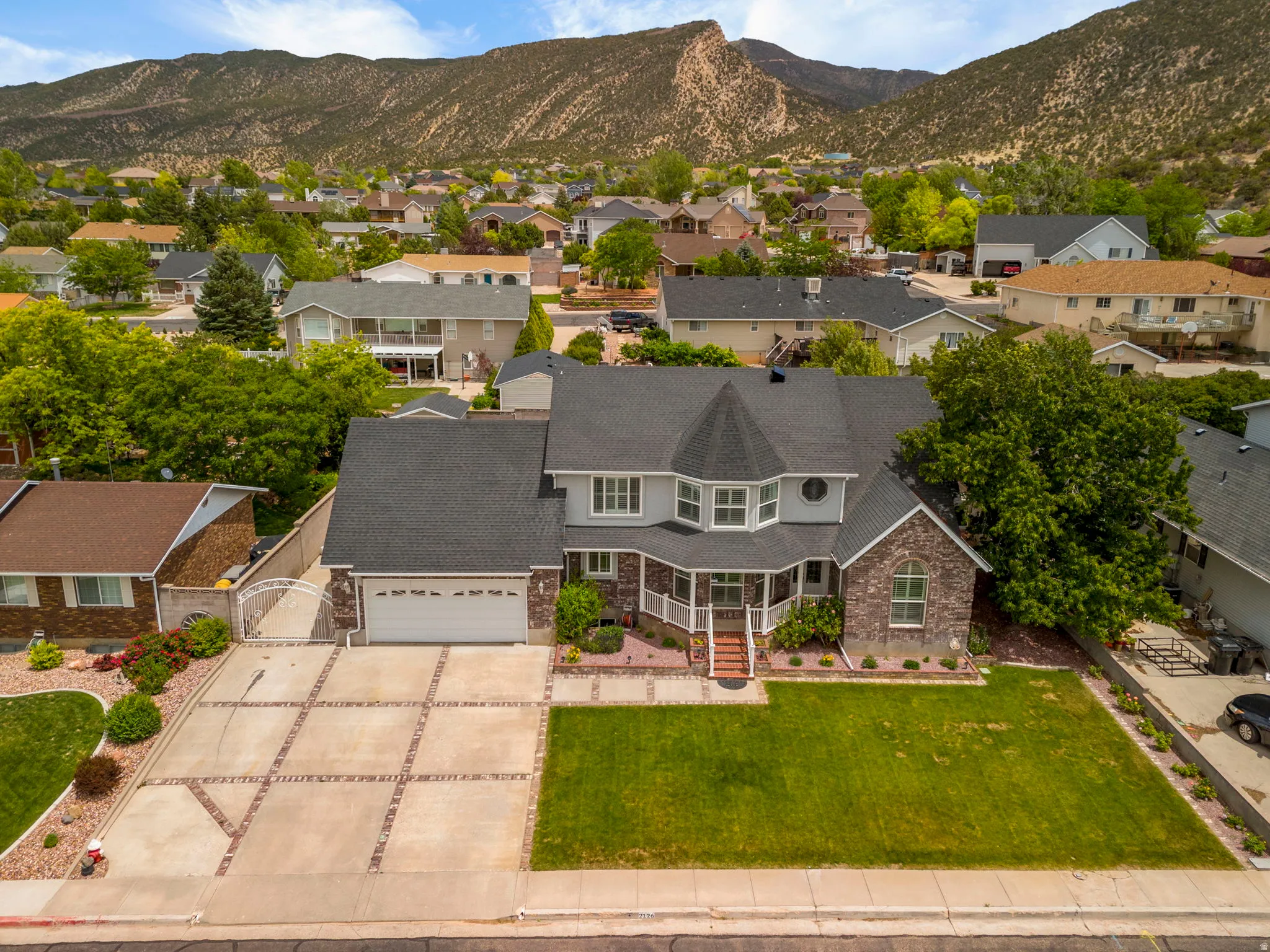 Two-story residence featuring a gray exterior with stone accents, a turret-style architectural element, and a covered porch