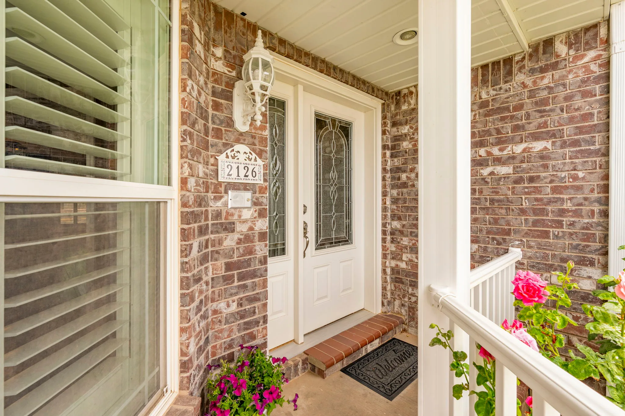 Brick exterior with a covered porch featuring a white support column and railing