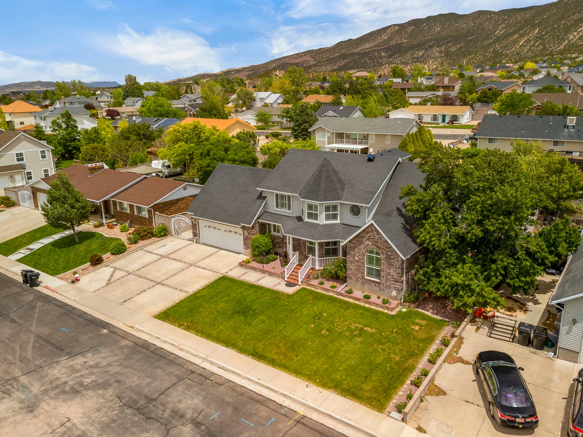 Two-story residence featuring a gray and brick exterior, a multi-gabled dark shingle roof, and a prominent bay window