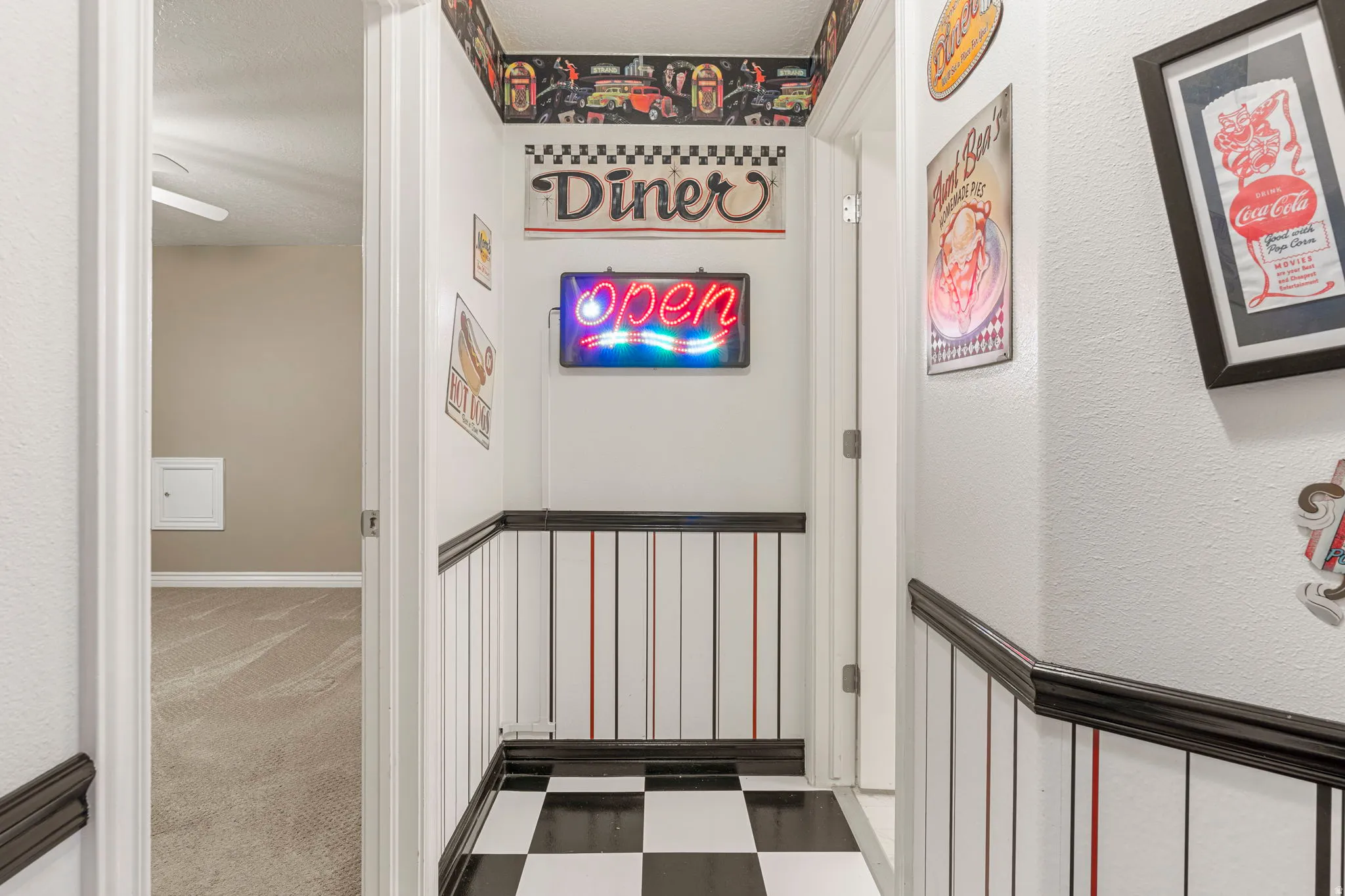 Hallway featuring checkerboard flooring, wainscoting, and white walls