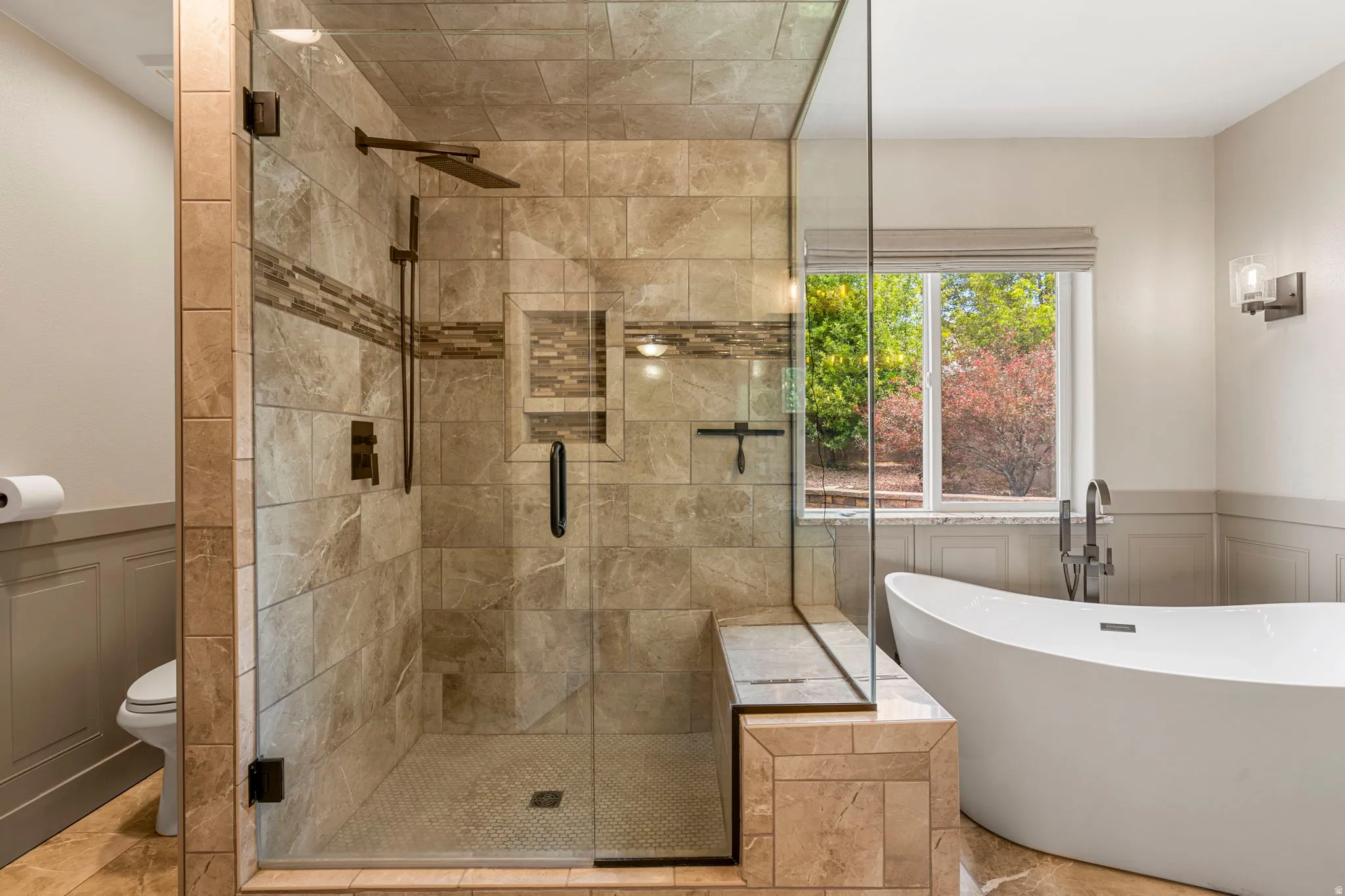 Glass-enclosed shower with tiled walls, integrated bench, and rainfall showerhead