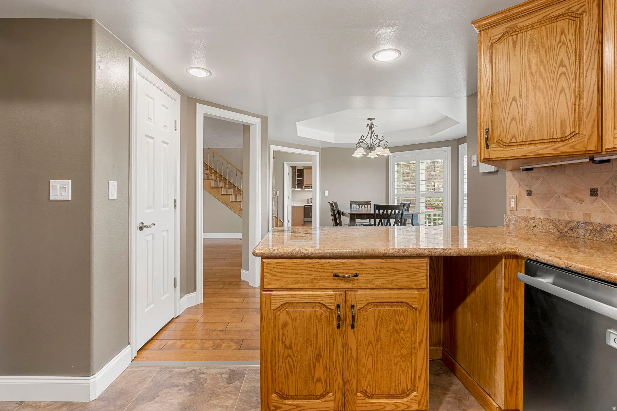 Kitchen featuring wood cabinetry, a granite-finish countertop, and a tile backsplash