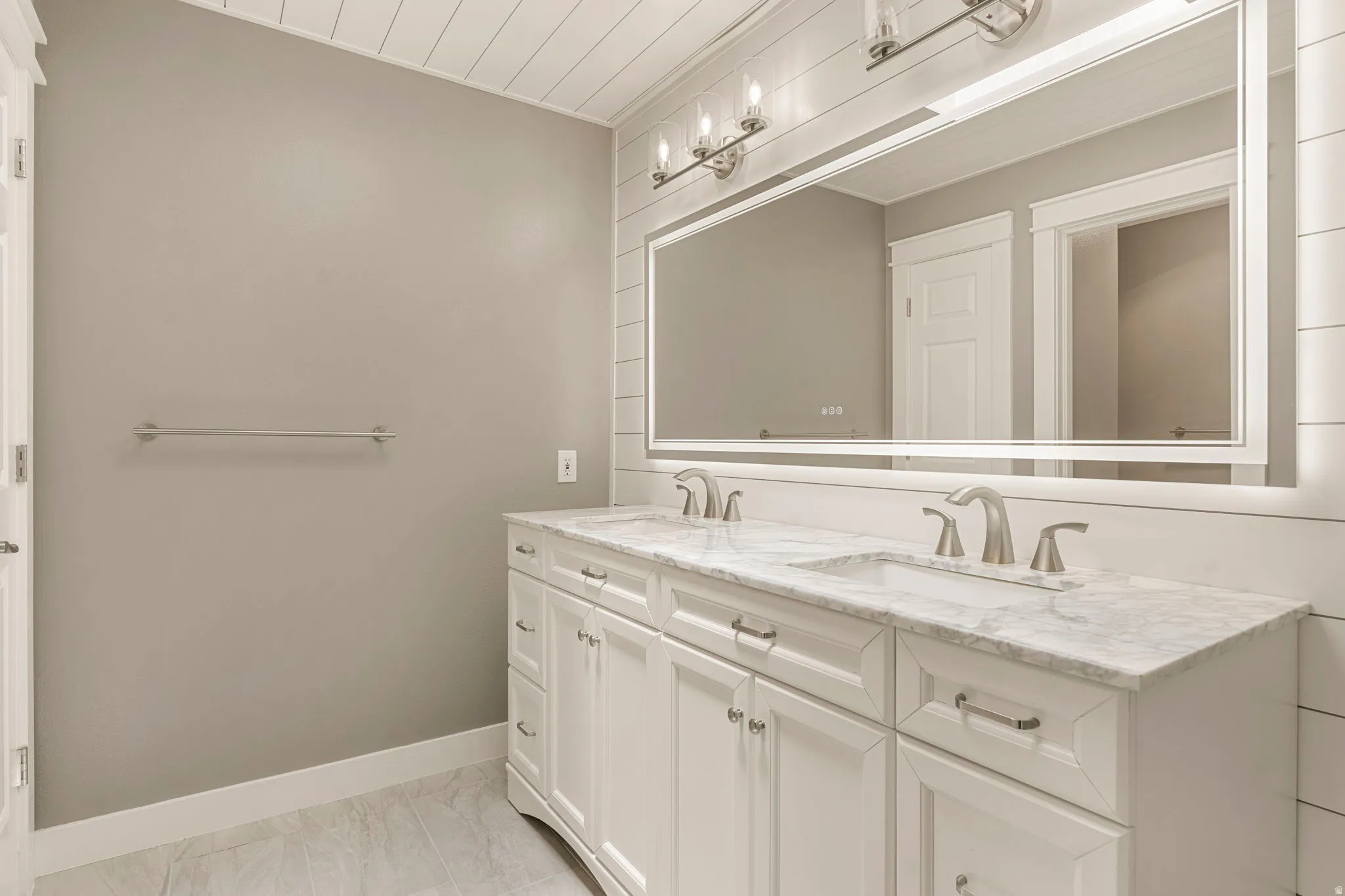 Double vanity featuring white cabinetry with brushed nickel hardware, integrated sinks, and stone countertops