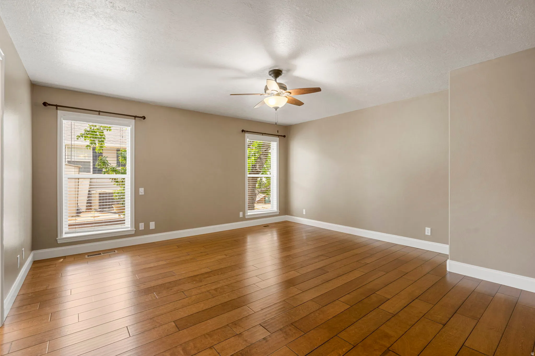 Spacious interior room featuring wood-finish flooring and neutral wall tones