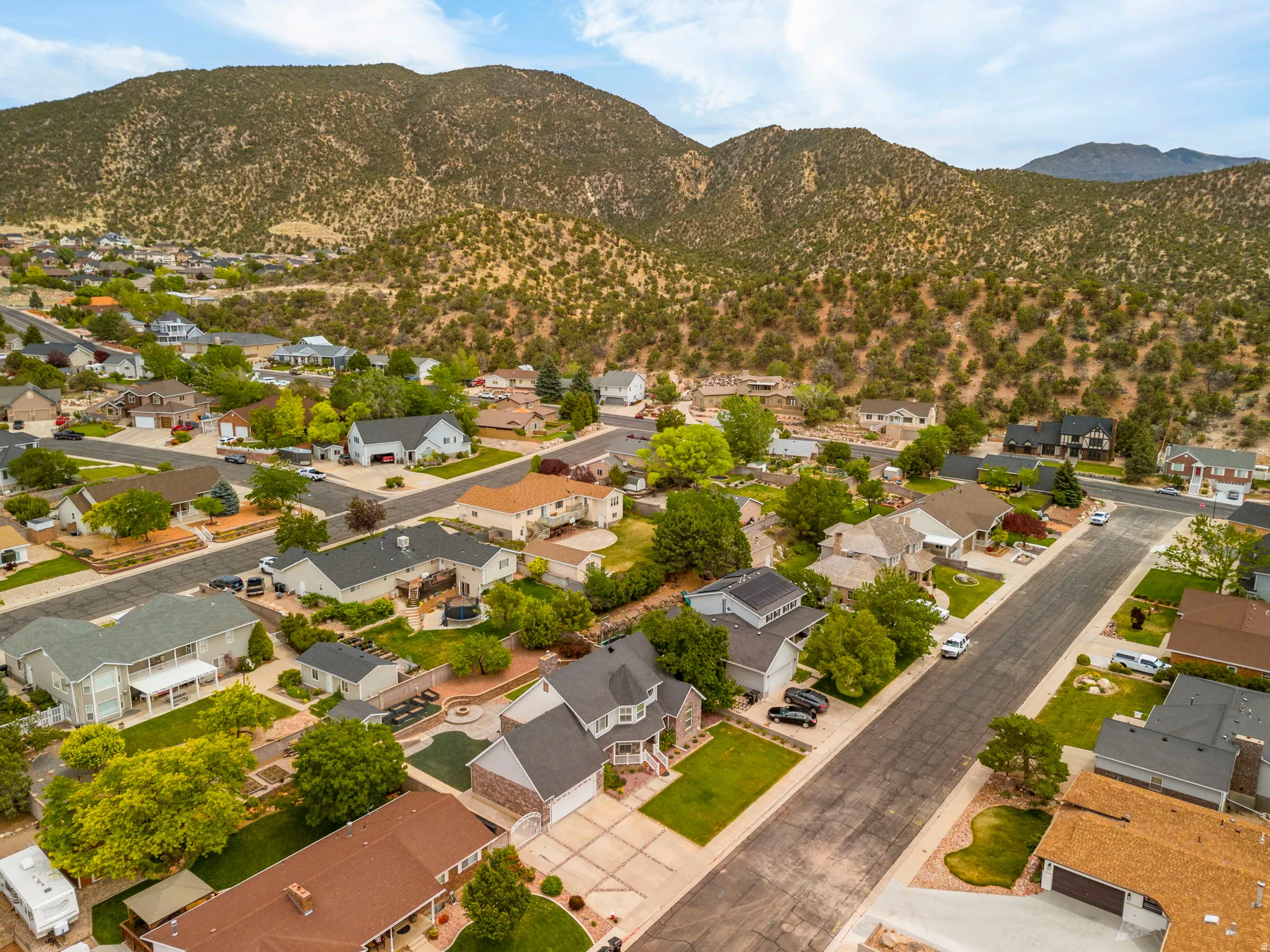 Residential neighborhood featuring mature trees, paved streets, and a mountainous backdrop