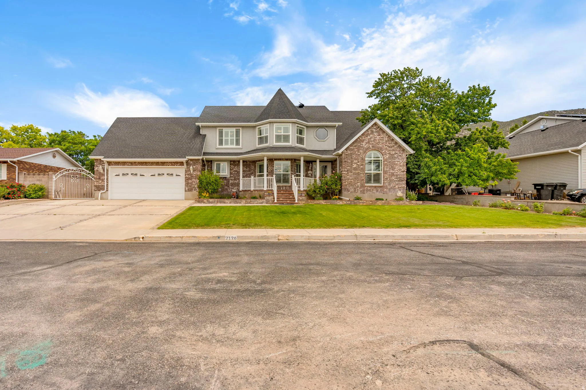 Stately two-story residence featuring a brick and siding facade, a prominent turret, and a covered front porch