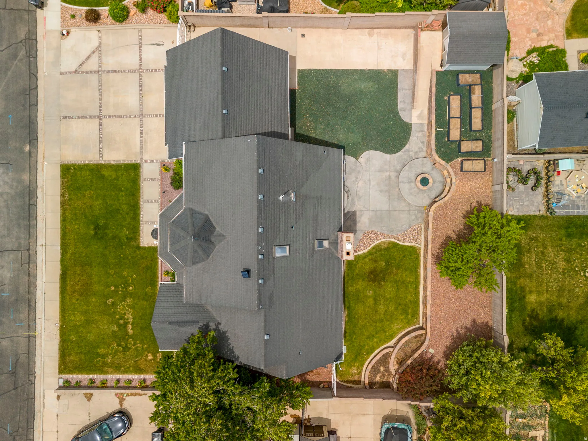 Expansive property featuring a meticulously landscaped backyard with a circular concrete patio, built-in fire pit, and a textured brick-patterned walkway