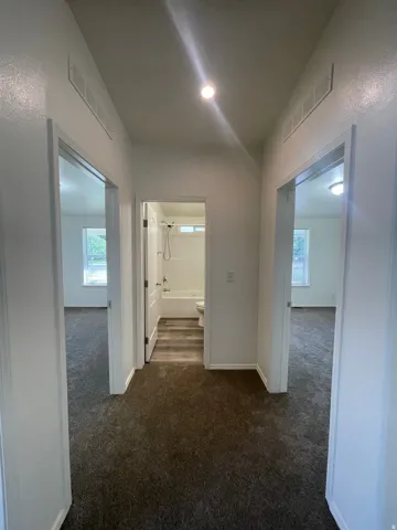 Central hallway featuring recessed lighting and dark carpeting