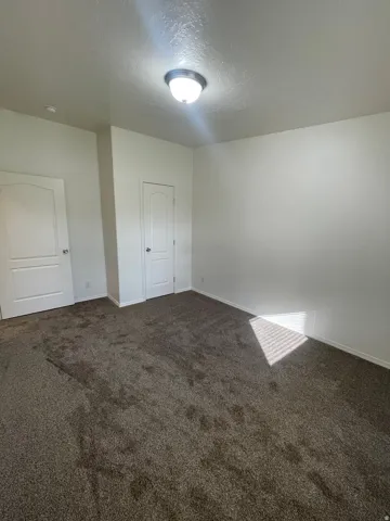 Neutral wall color, textured carpet, white interior doors, and a flush mount ceiling light