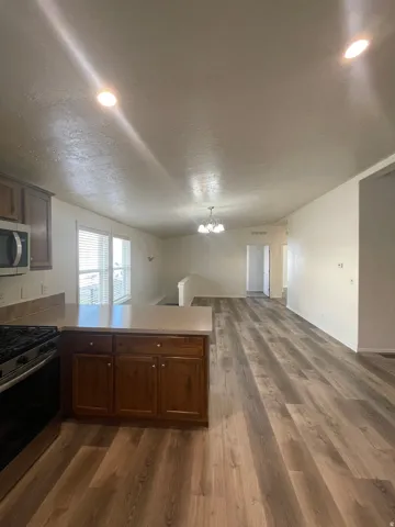 Open-concept living space with wood-finish flooring, recessed lighting, and a kitchen island featuring wood cabinetry