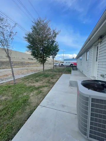 Siding exterior with an outdoor light fixture, concrete walkway, and an HVAC unit