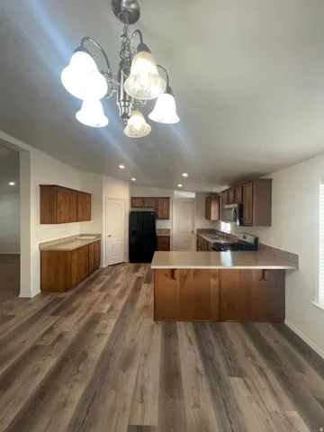 Open-concept kitchen with wood-finish flooring, recessed lighting, wood cabinetry, and a central island with countertop seating