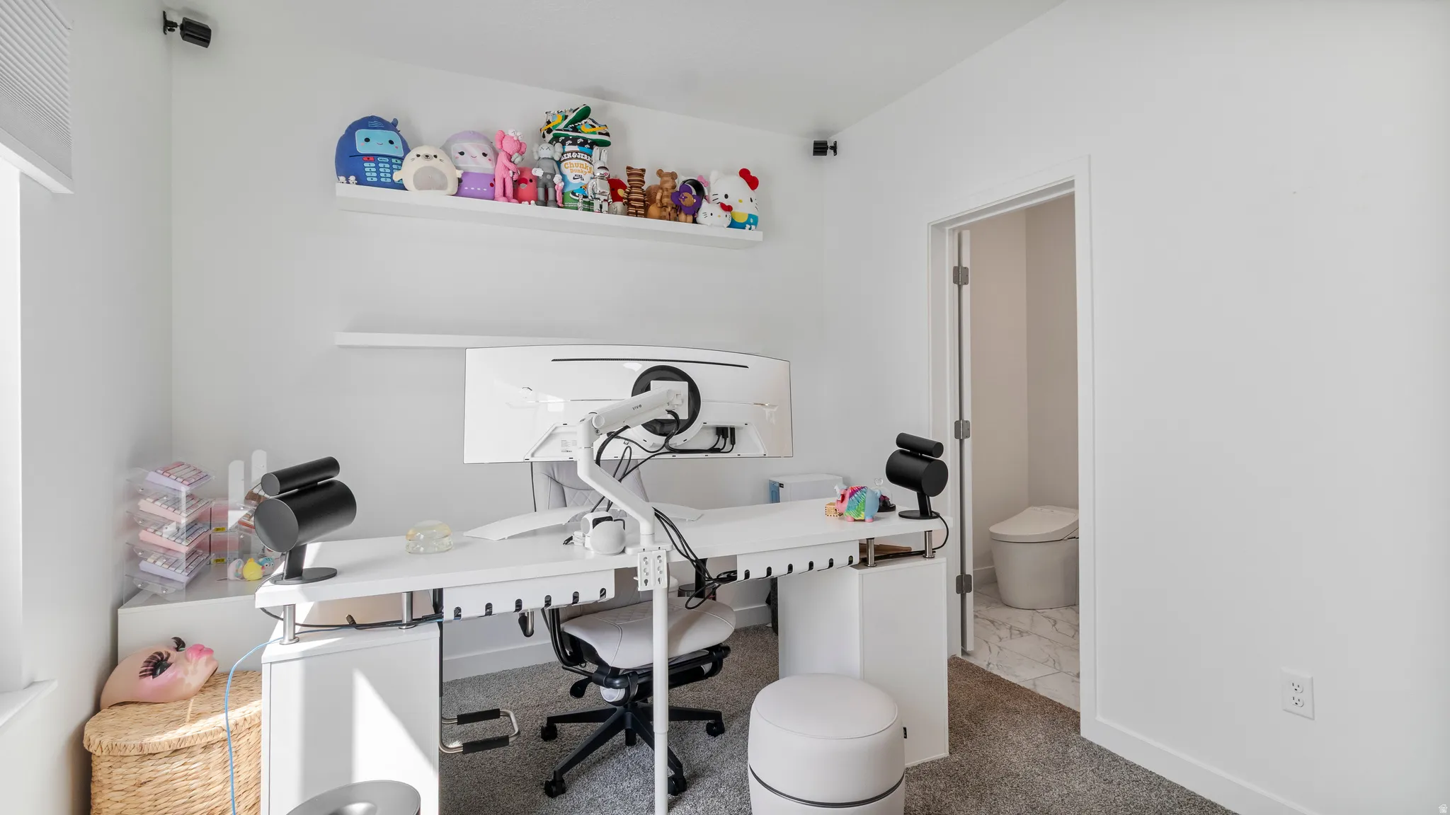 Dedicated workspace featuring a white floating desk, integrated shelving, and wall-mounted monitors