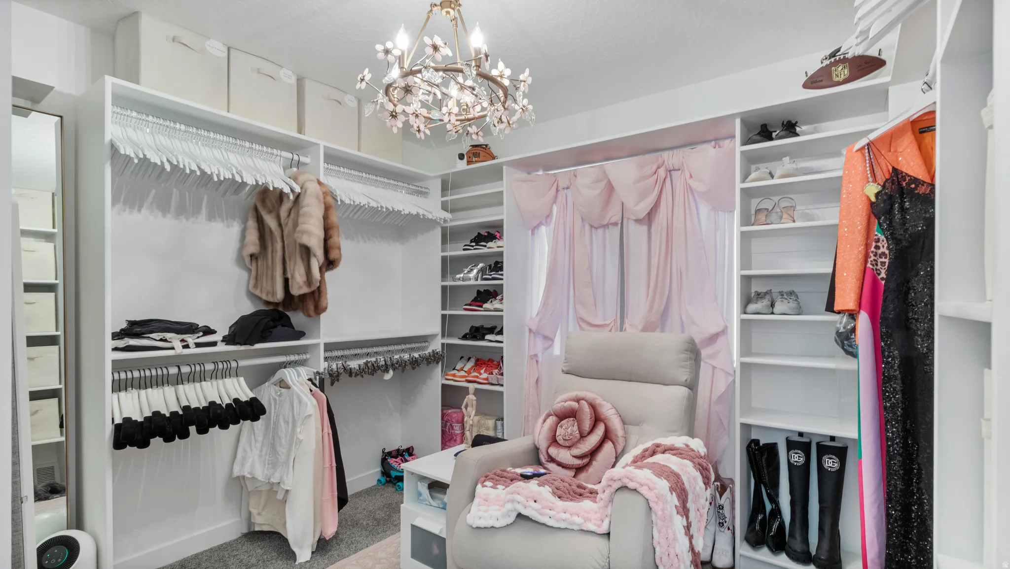 Custom closet system featuring extensive shelving, multiple hanging rods, built-in shoe racks, a full-length mirror, and a decorative chandelier