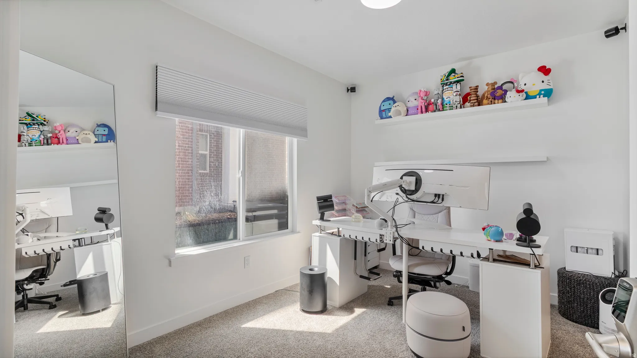 Neutral tone white walls, light gray carpet flooring, and a large window with privacy blinds