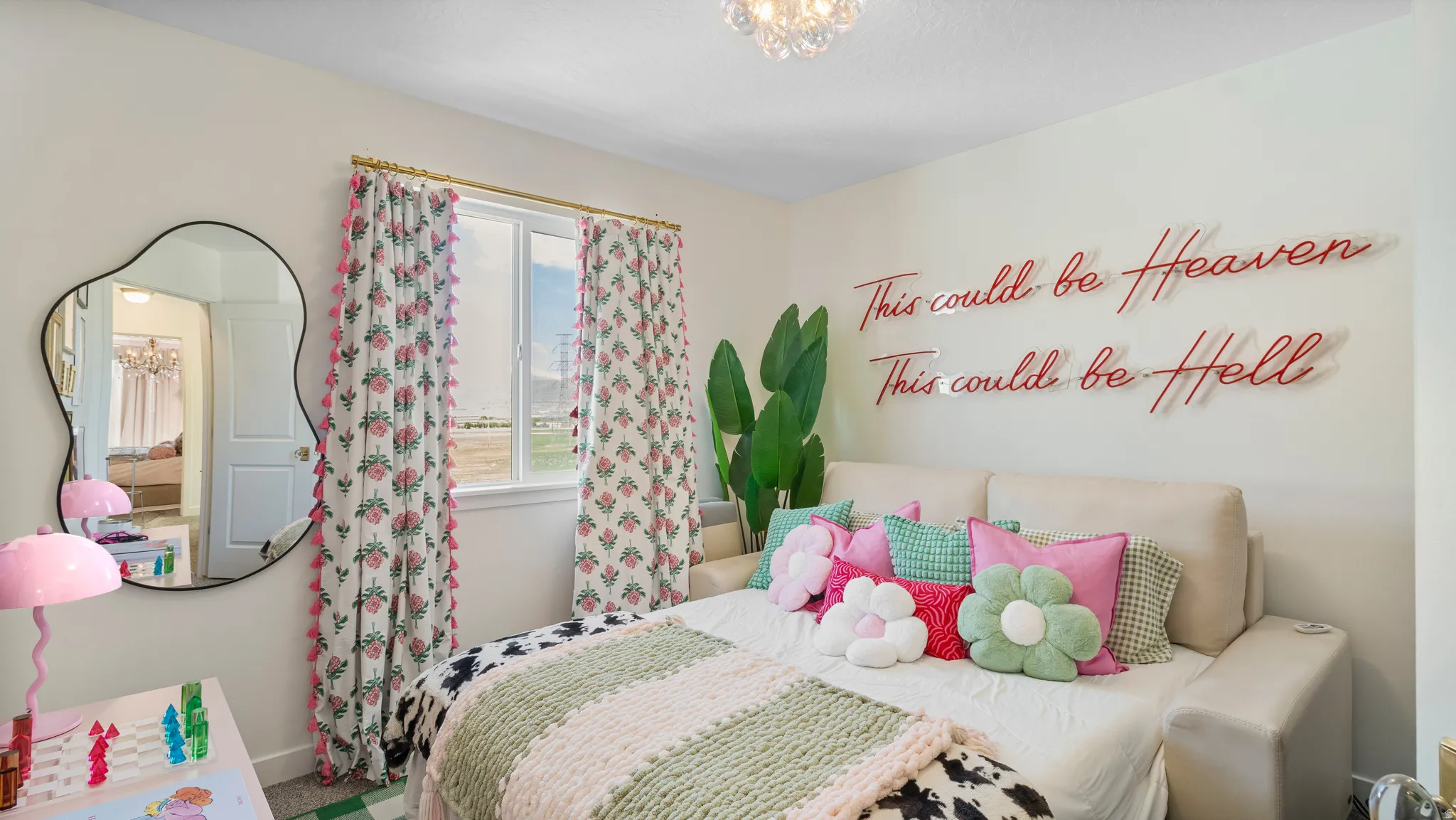 Neutral wall paint, a window with decorative curtains, a decorative wall mirror, and a ceiling-mounted light fixture