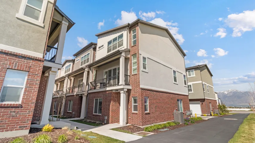 Multi-level townhome featuring a brick and stucco exterior