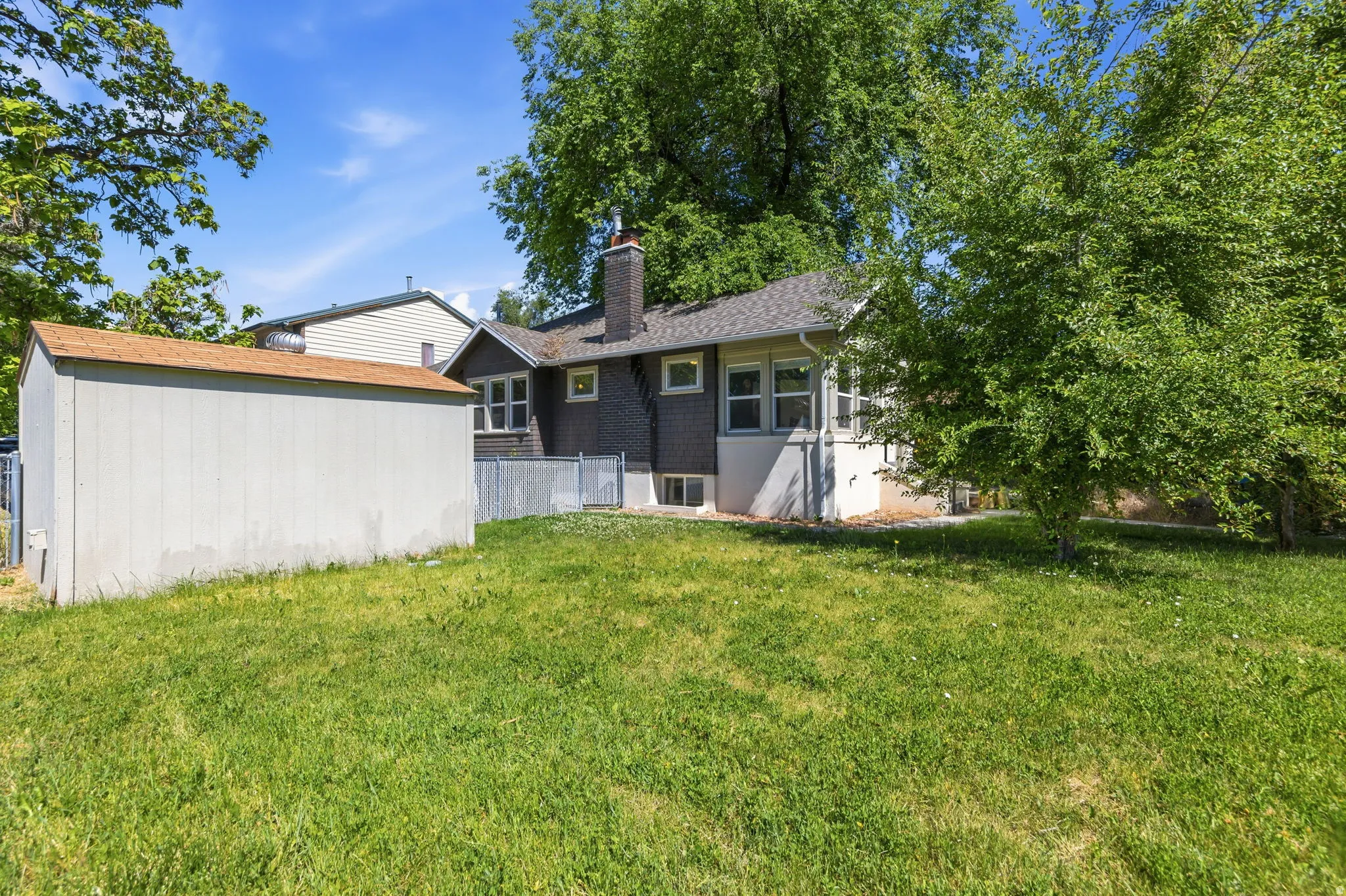 Expansive grassy yard with mature trees and a detached shed