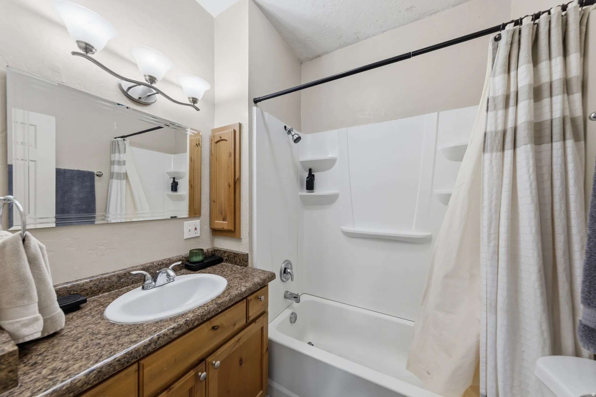 Bathroom featuring a vanity with a large mirror, integrated sink, and an overhead three-light fixture