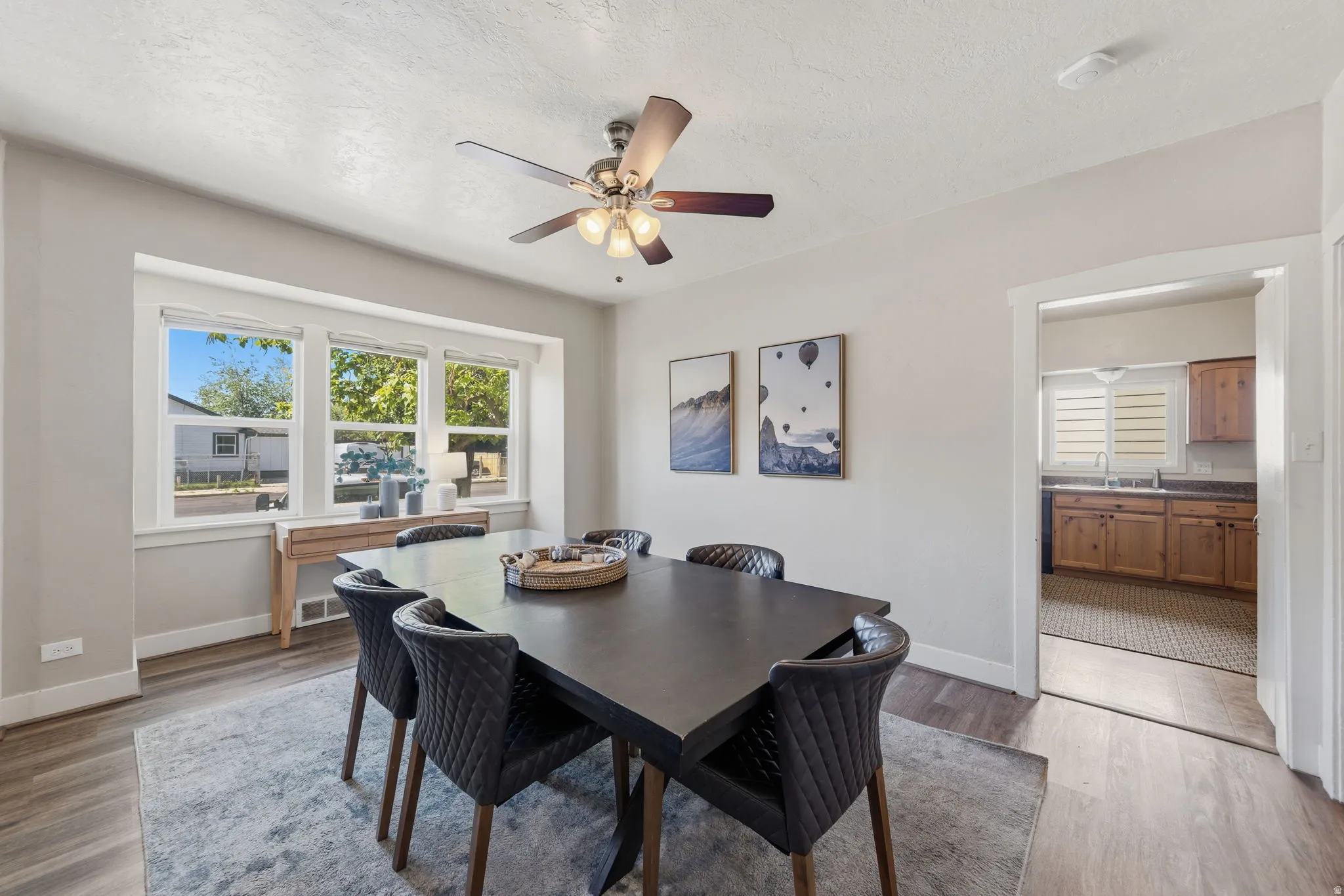 Dining area featuring wood-finish flooring, a contemporary ceiling fan with integrated lighting, and a multi-paned window