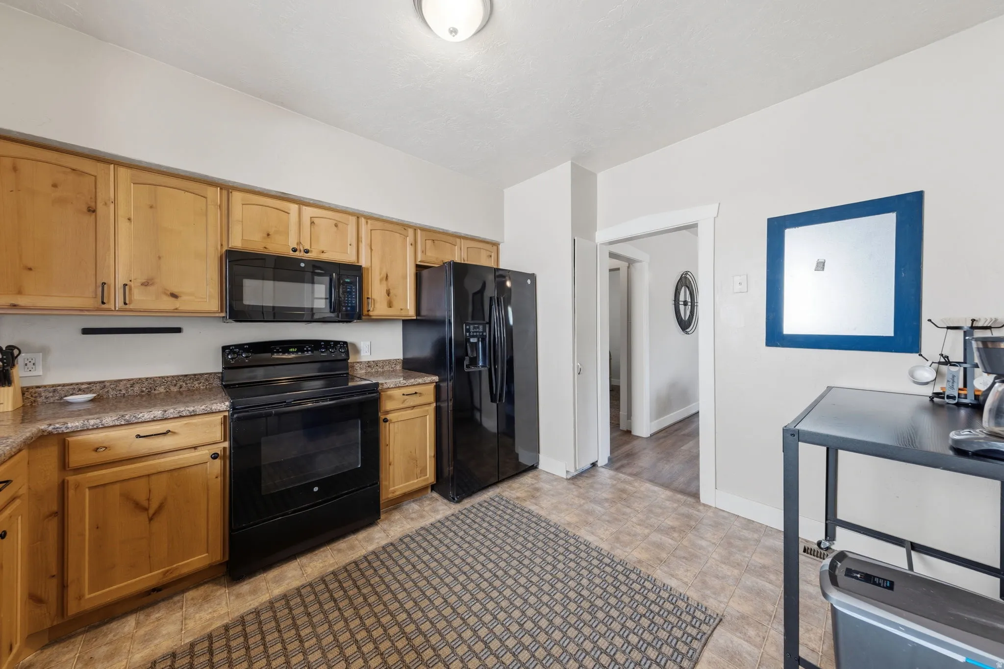 Kitchen featuring natural wood-finish cabinetry, black appliances, and laminate countertops