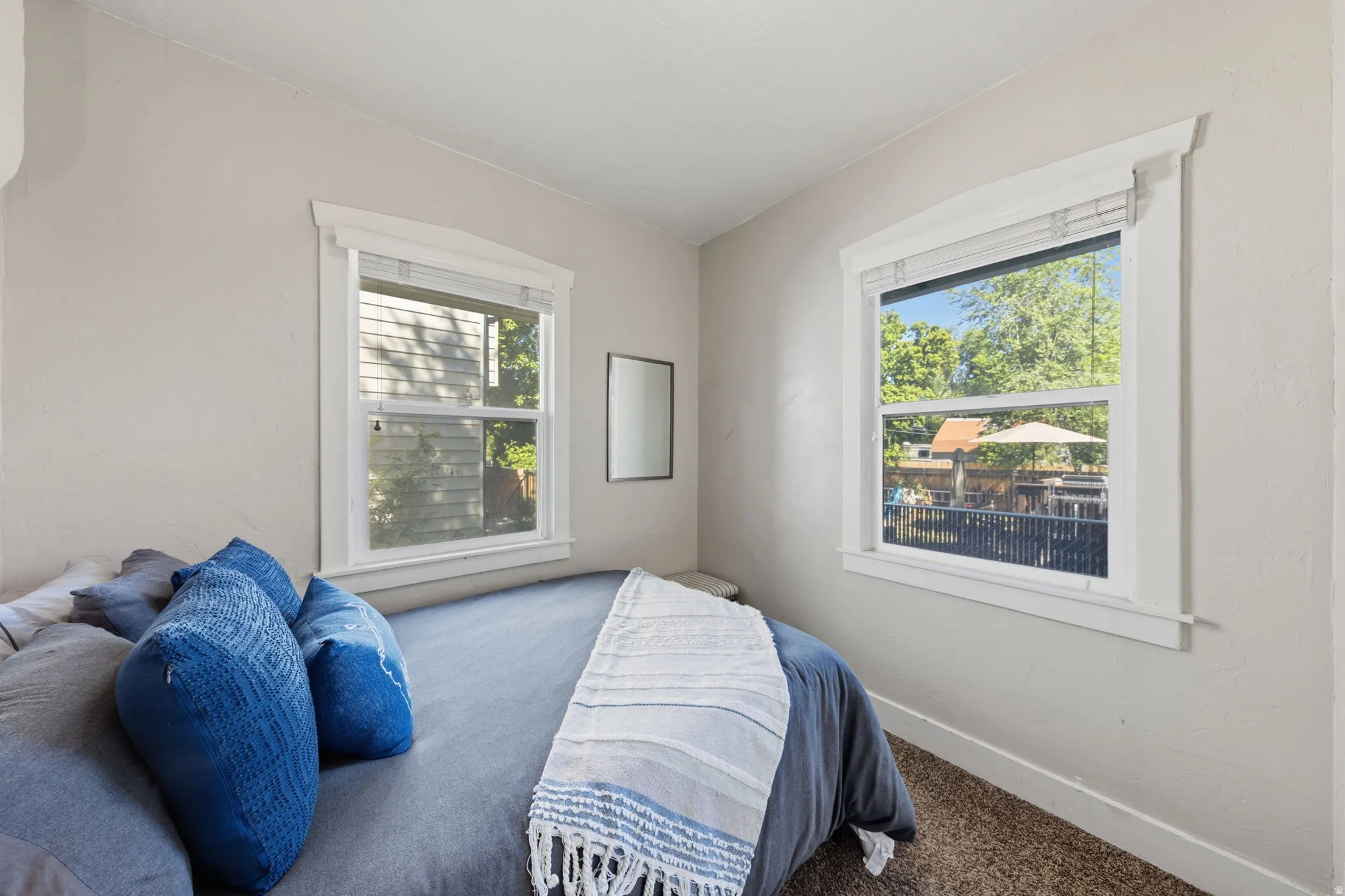 Neutral wall paint finish in a bedroom with two windows featuring white trim