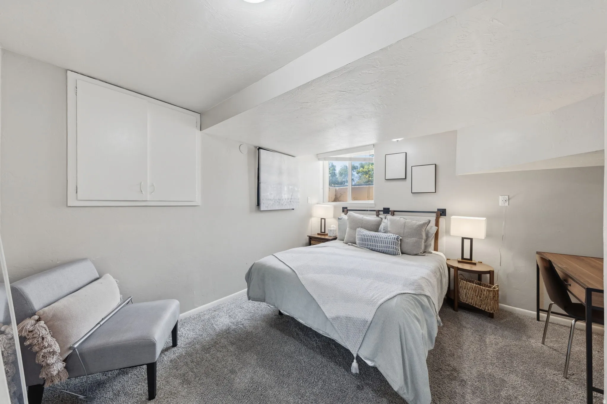 Bedroom featuring light gray walls, gray carpeting, and a window with natural light