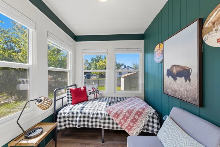 Bright room featuring multiple windows, a paneled accent wall, wood-finish flooring, and a white beadboard ceiling